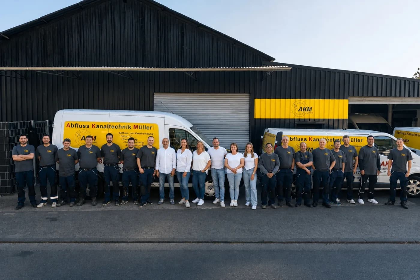Vollständiges Team der Abfluss Kanaltechnik Müller GmbH vor den Einsatzfahrzeugen