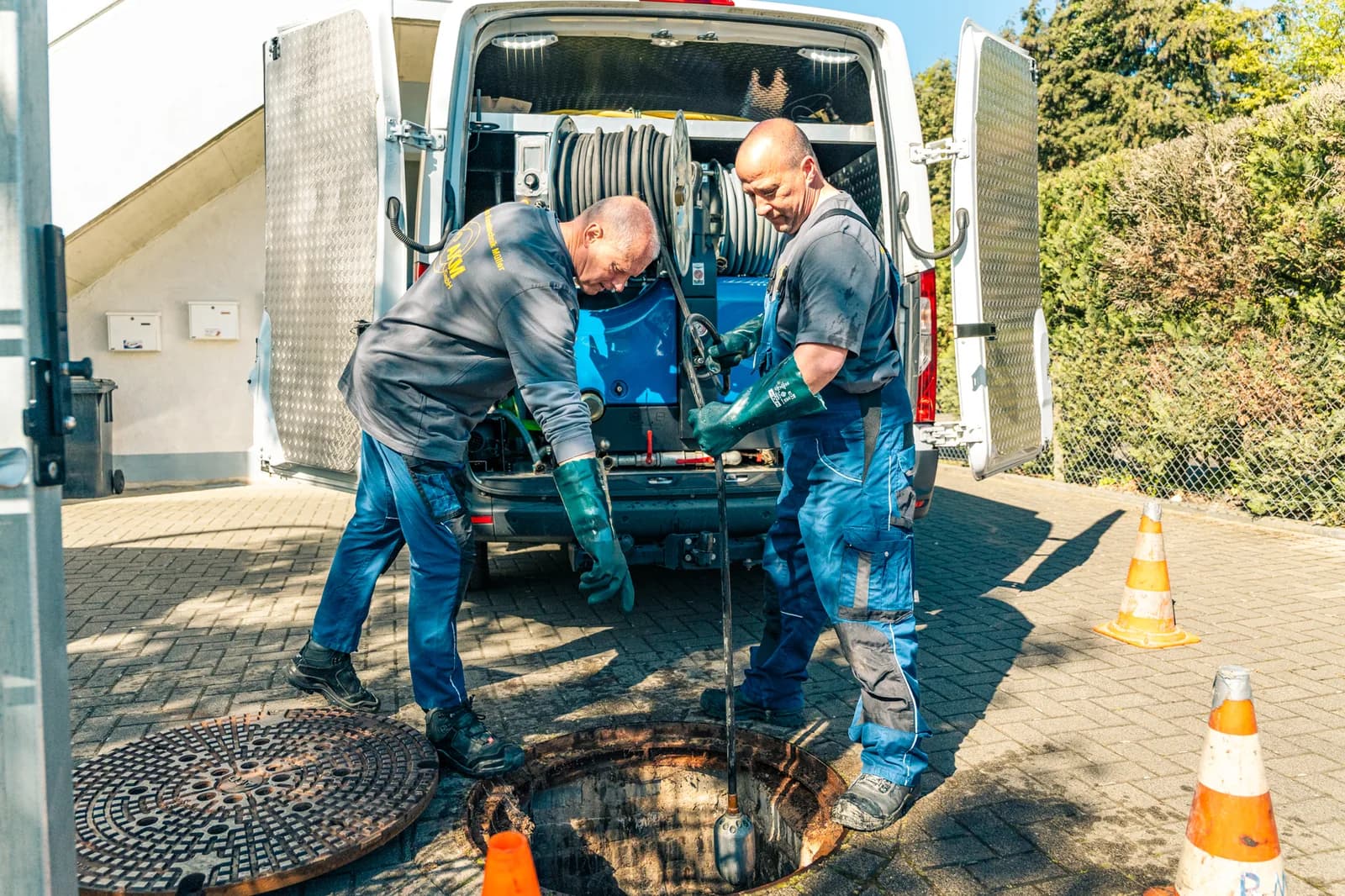 Techniker reinigt Kanal per Hochdruckspülung am Haus